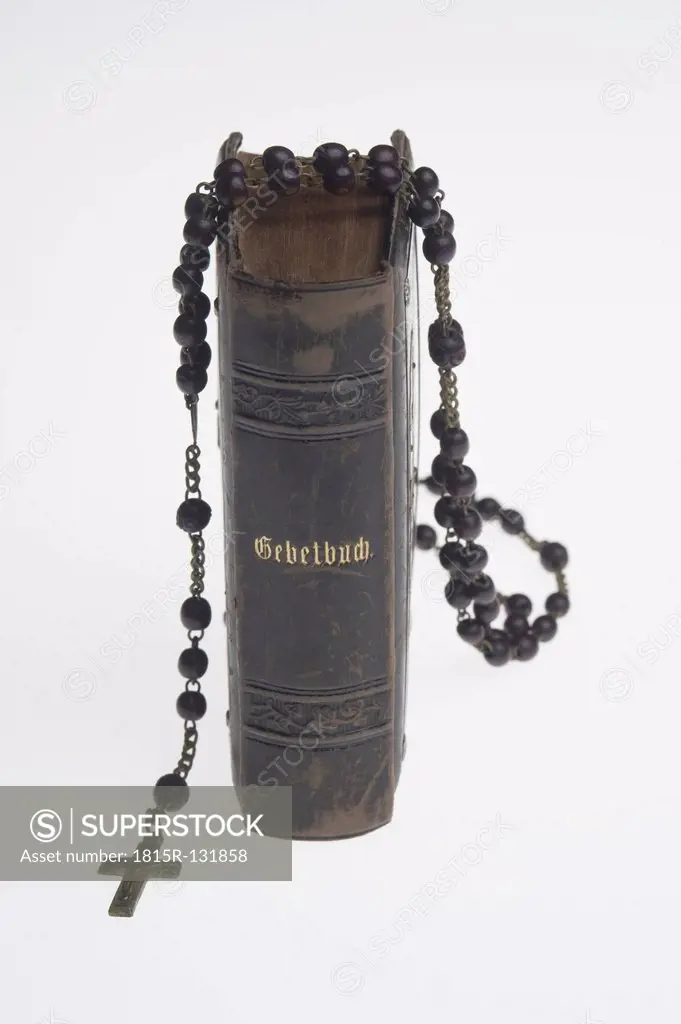 Bible with rosary on white background, close up