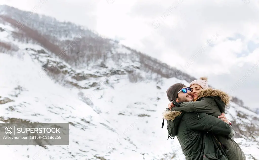 Spain, Asturias, couple hugging each other in the snowy mountains