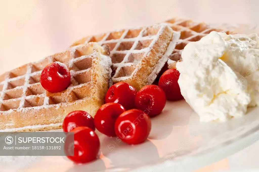 Wafers with icing sugar, whipped cream and cherries, close up