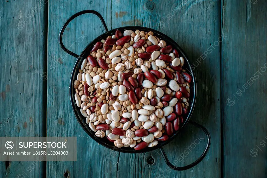 Skillet of different dried pulses on wood