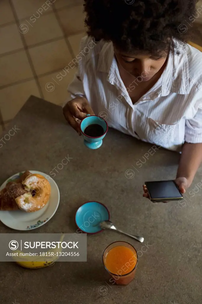 Top view of young woman with espresso cup looking at her phablet