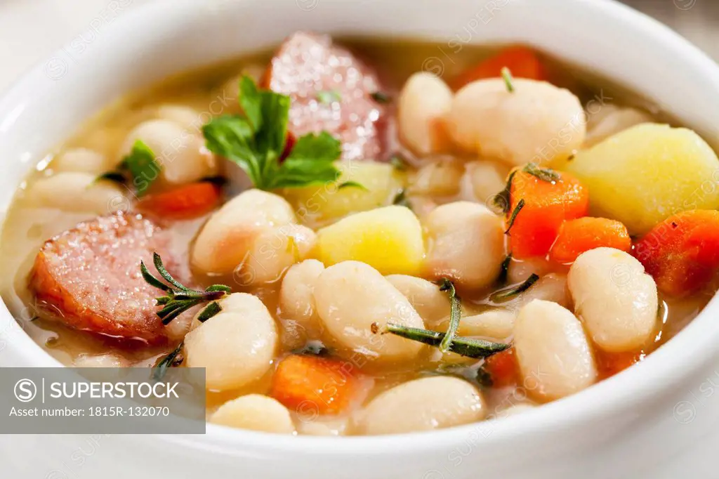 Bowl of white bean soup with smoked sausage, close up