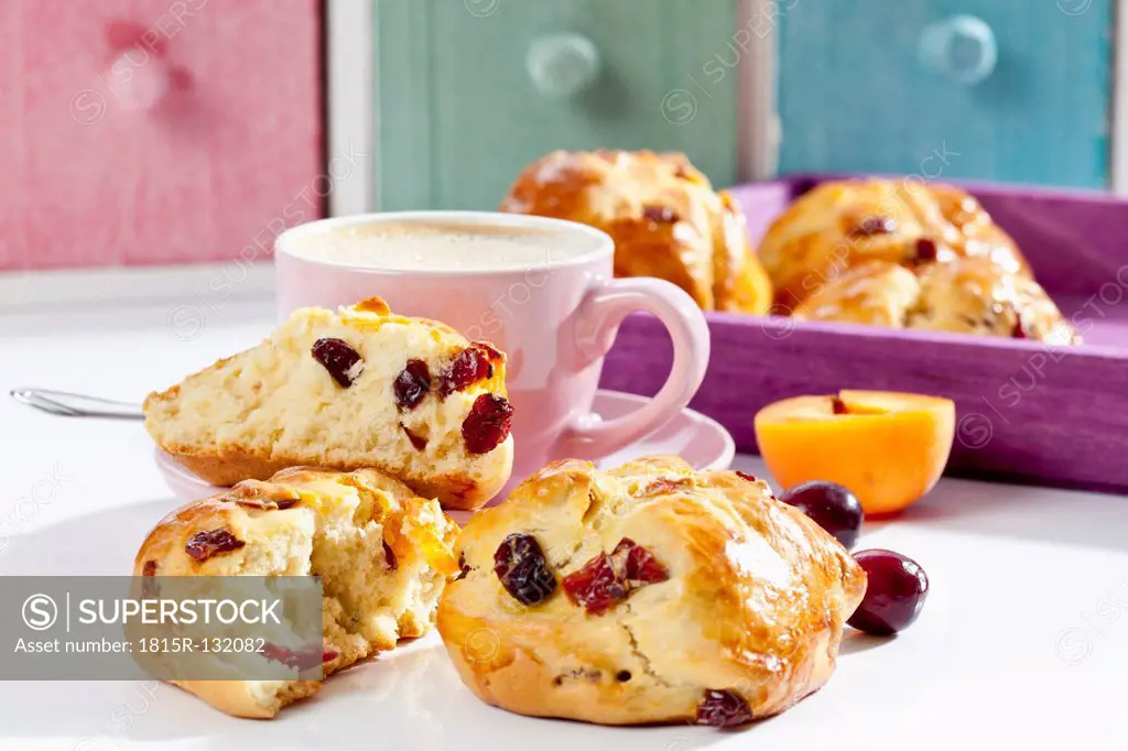 Cranberry scones with apricot and cup of coffee on wooden tray, close up