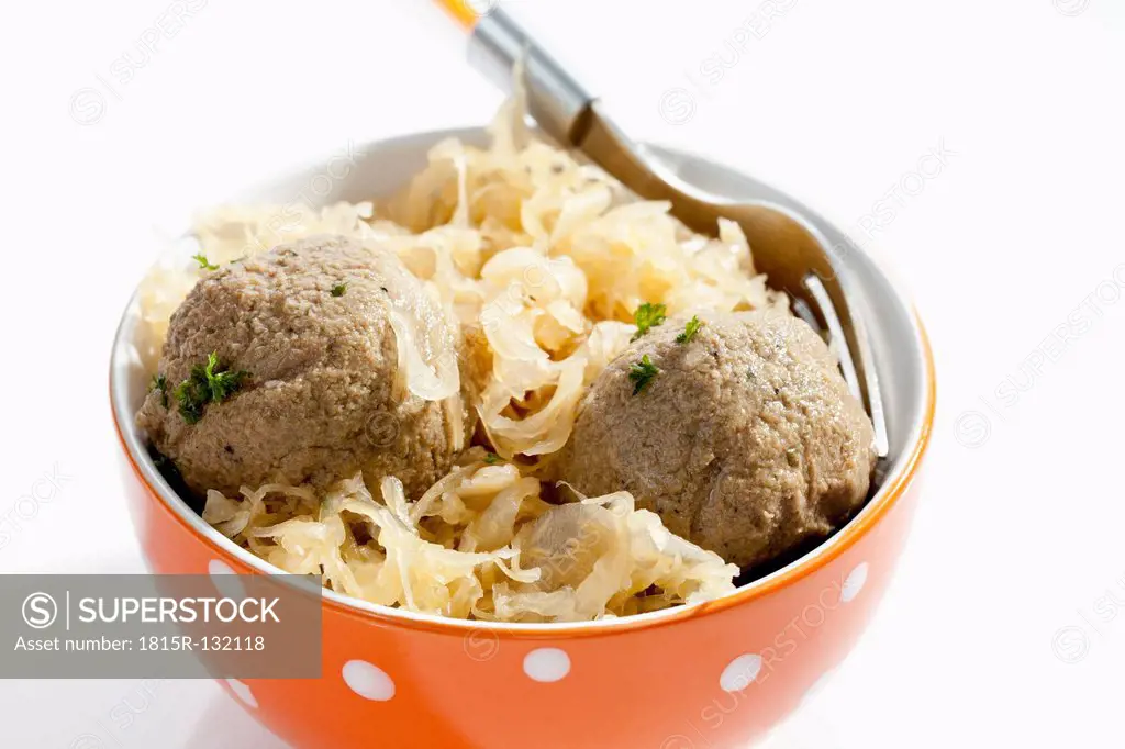 Bowl of liver dumplings with sauerkraut on white background, close up