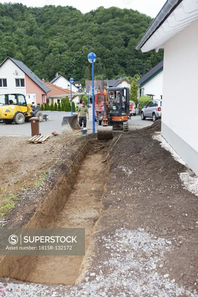 Europe, Germany, Rhineland Palatinate, Men working with excavator during house building
