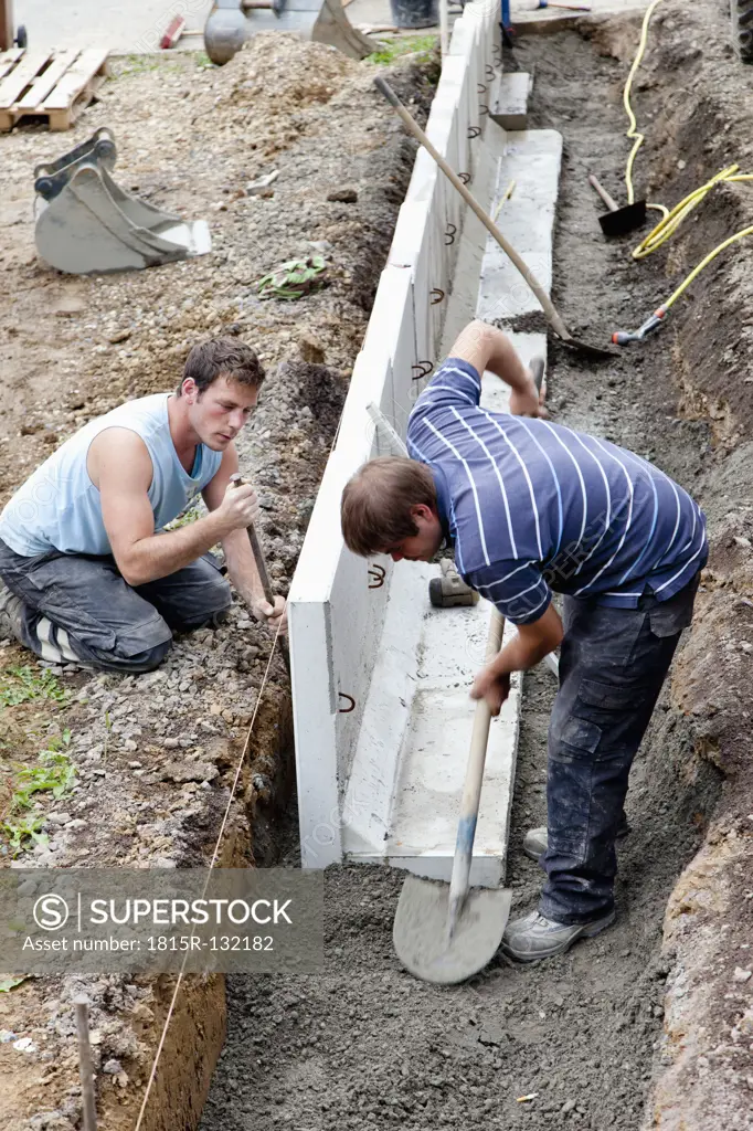 Europe, Germany, Rhineland Palatinate, Men installing corner stone in soil while house building