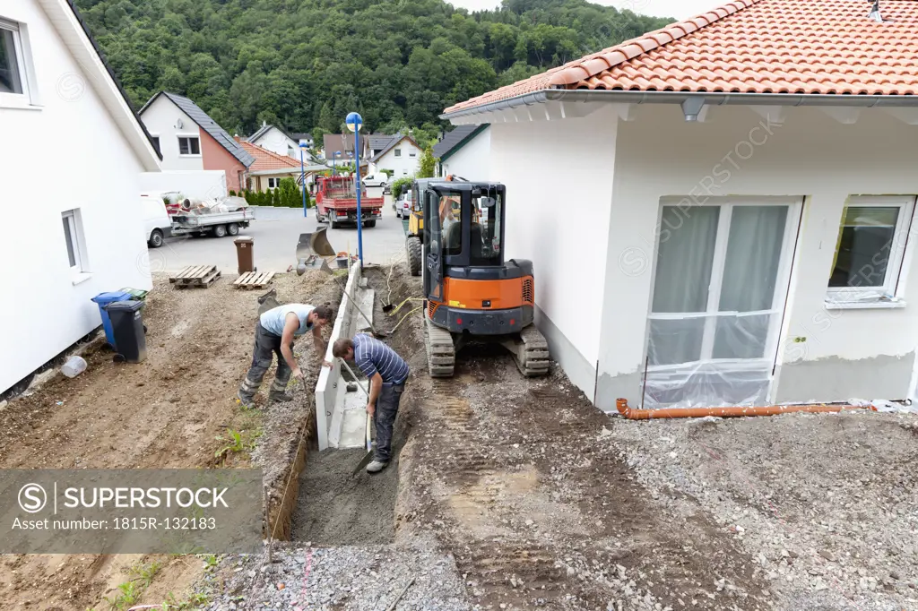 Europe, Germany, Rhineland Palatinate, Men installing corner stone in soil while house building