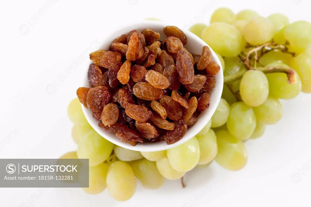 Bowl of sultanas with green grapes on white background, close up