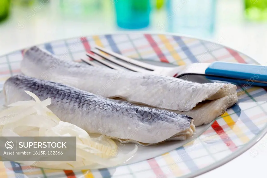Herring with onions and vinegar on plate, close up