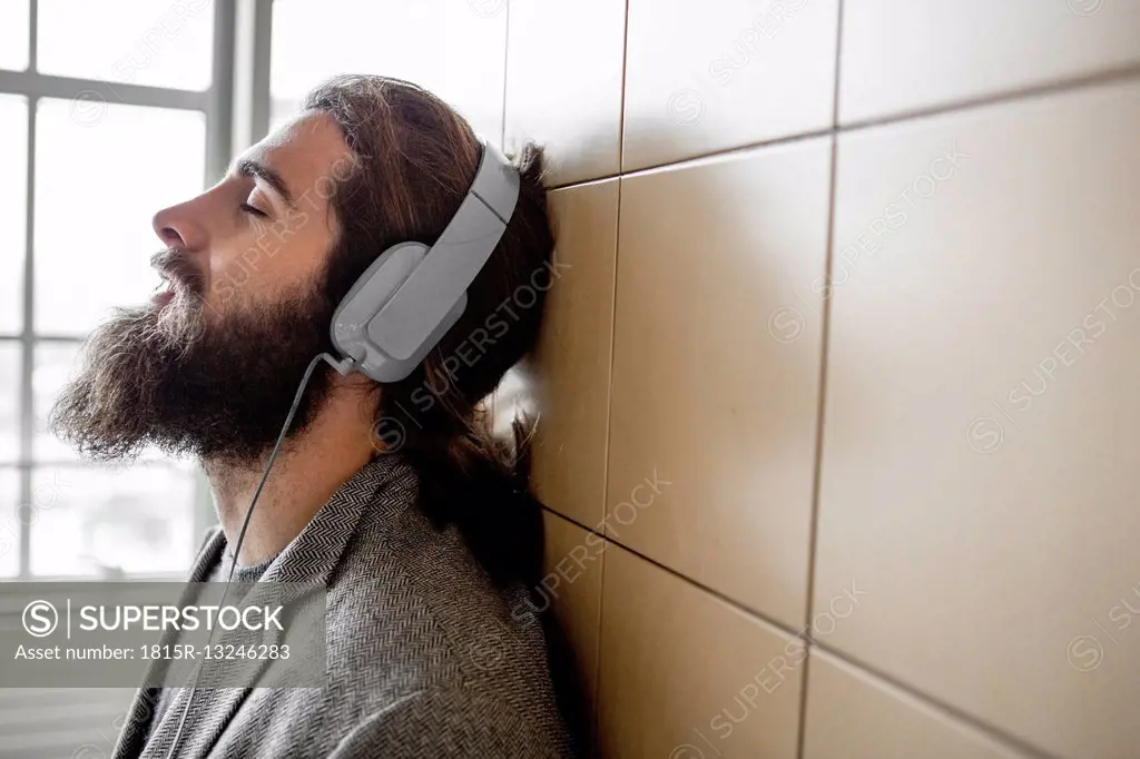 Young bearded man listening music with headphones