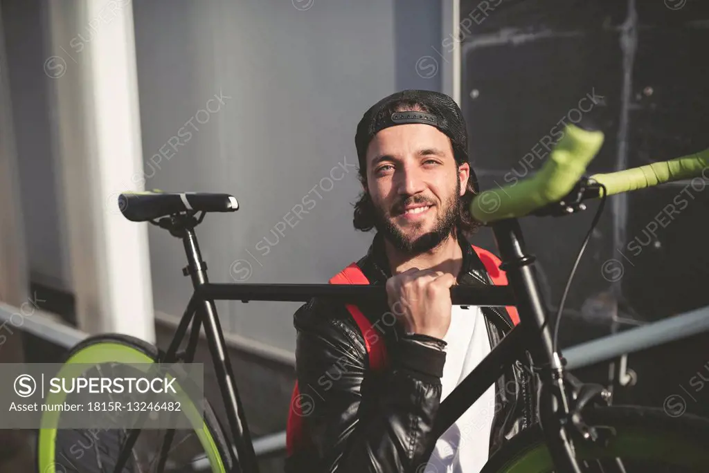 Smiling young man carrying fixie bike