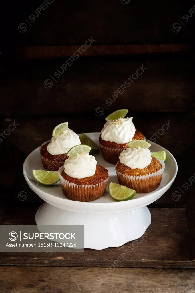 Four lime cup cakes with cream cheese topping on cake stand
