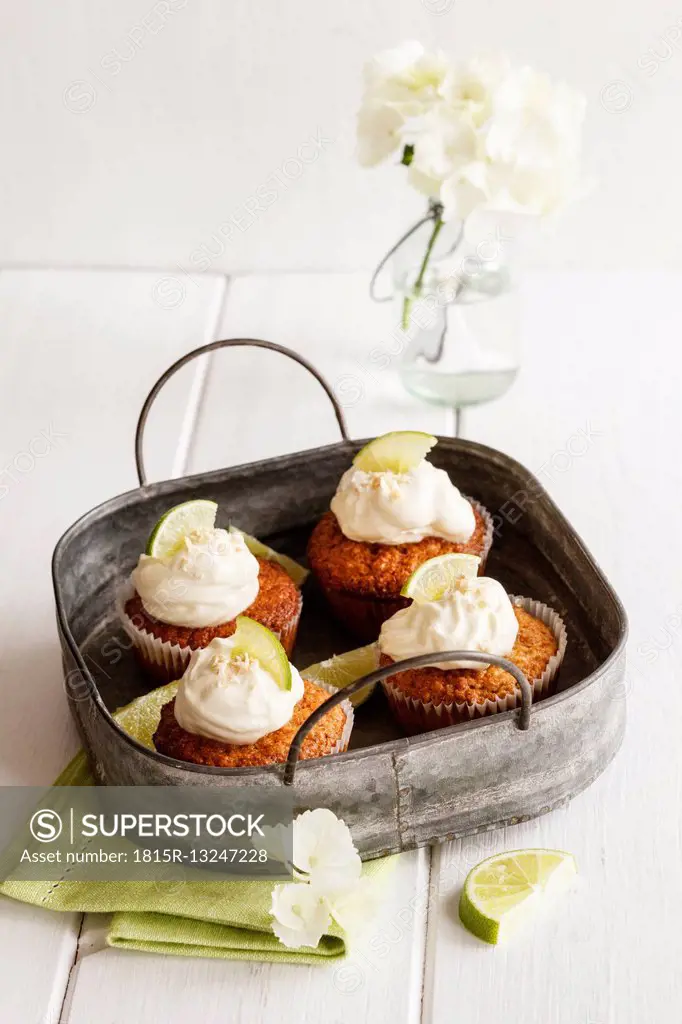 Four lime cup cakes with cream cheese topping on metal tray