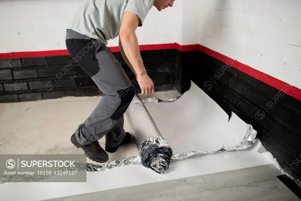 Young man placing a insulating material for a laminate flooring