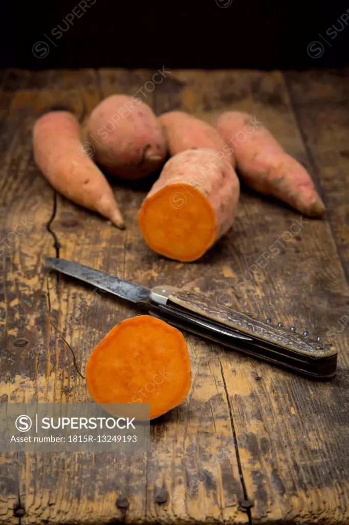 Sliced and whole sweet potatoes on dark wood