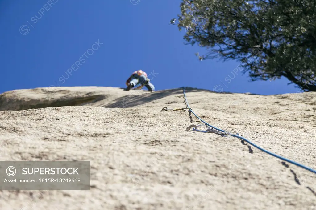 Quickdraws with a rope with climber in the background