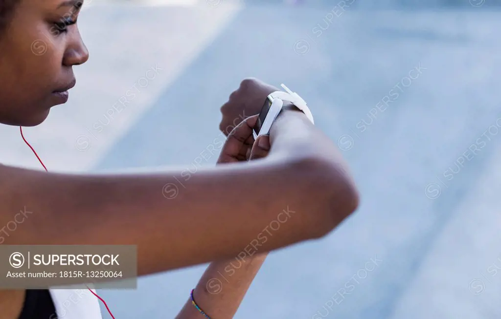 Young woman outdoors looking at smartwatch