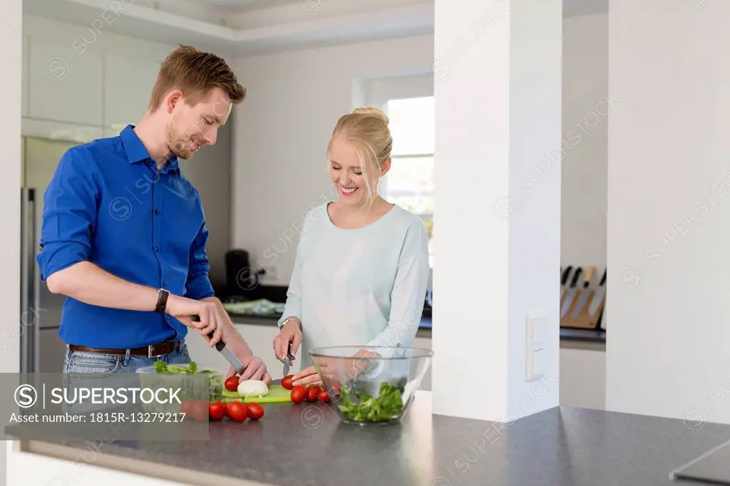 Couple in kitchen preparing a salad