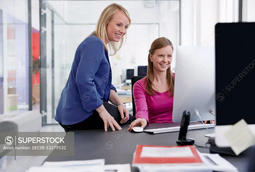 Two women working at computer in office