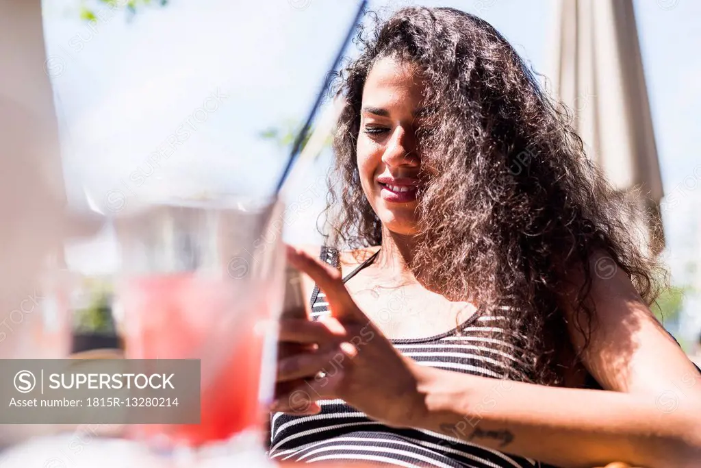 Smiling young woman looking at cell phone outdoors