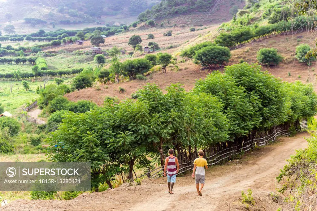 Indonesia, Sumbawa island, Two young men walking on a dirt road