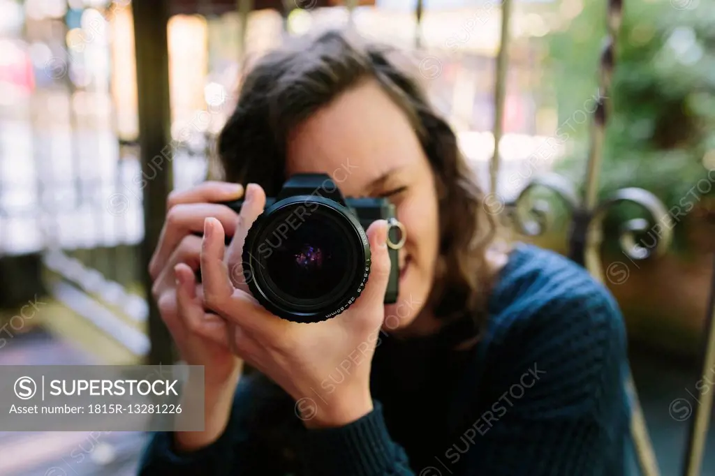 Young woman on balcony using vintage camera