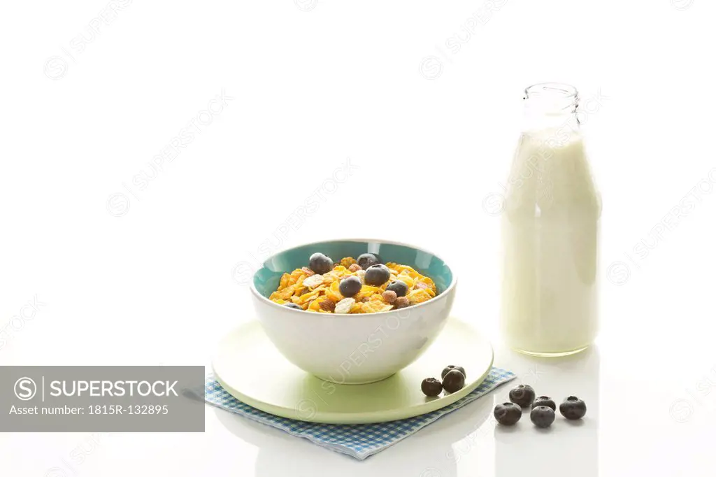 Bowl of healthy cereals with milk jar on white background