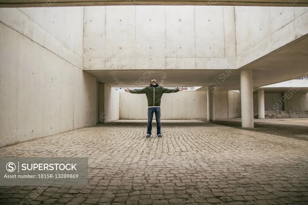 Man with arms outstretched and head back in modern architecture