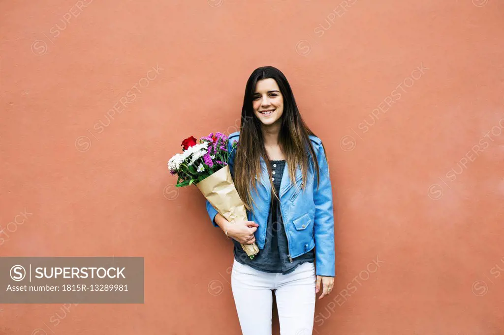 Smiling young woman holding bunch of flowers