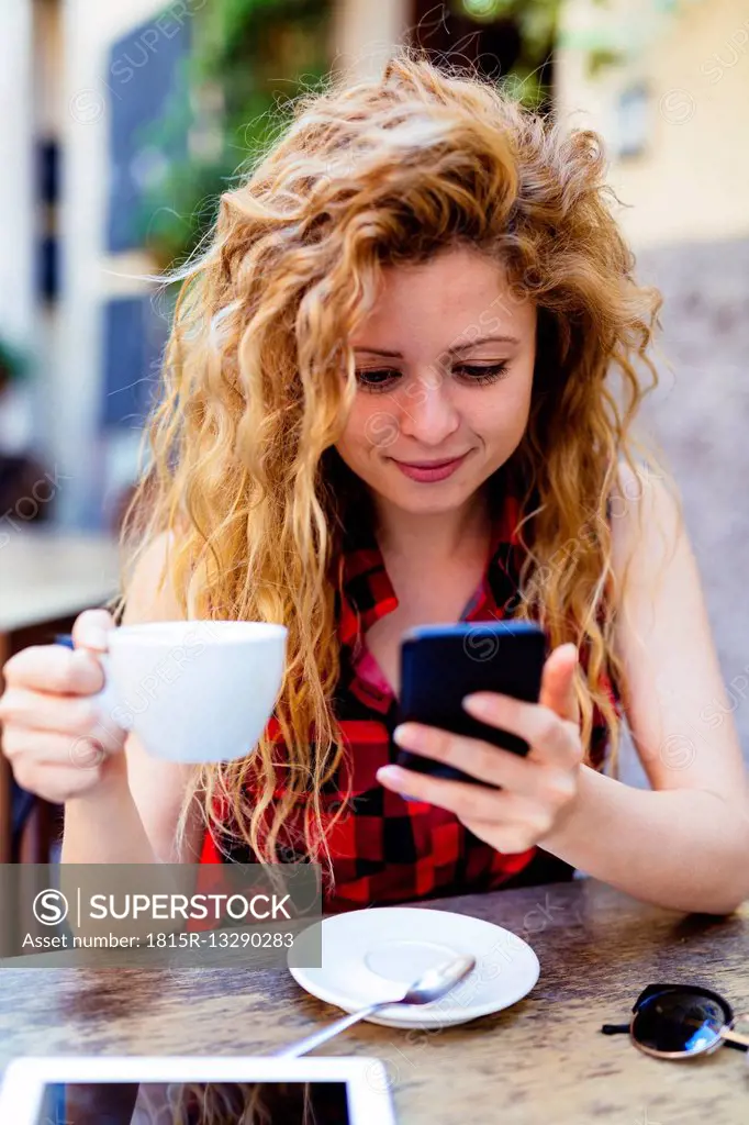 Woman at outdoor cafe looking at cell phone
