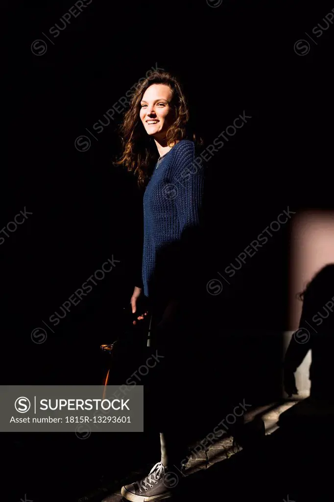 Portrait of smiling woman standing in between shadows