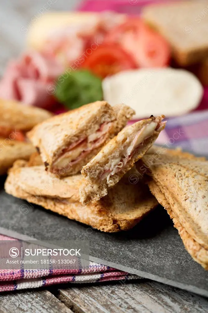Ham and cheese sandwich with tomatoes on chopping board