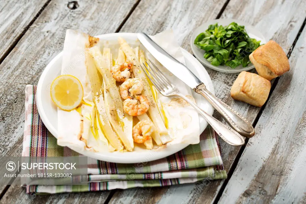 King prawns with white asparagus and basil on plate, close up