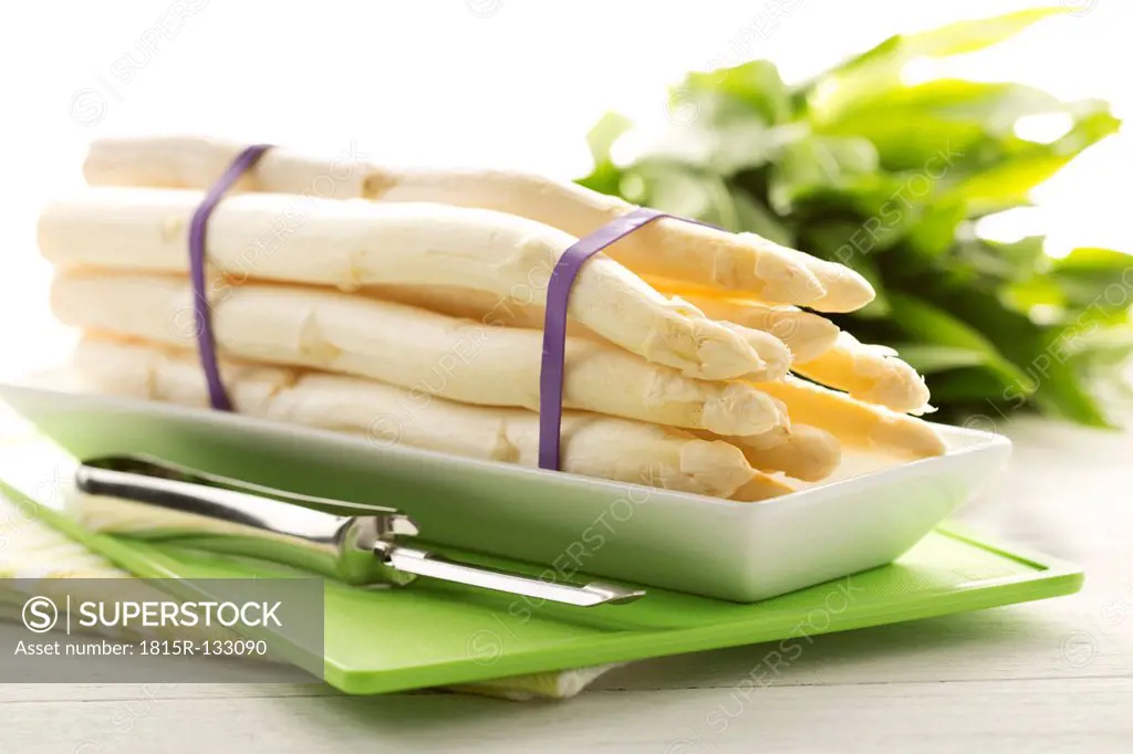 Bundle of white asparagus and wild garlic on chopping board, close up
