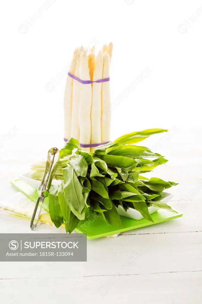 Bundle of white asparagus and wild garlic on chopping board, close up