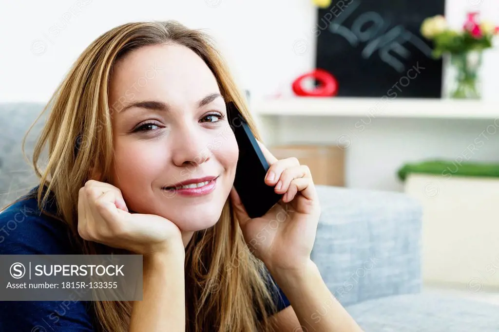 Germany, Bavaria, Munich, Portrait of young woman talking on mobile phone, smiling