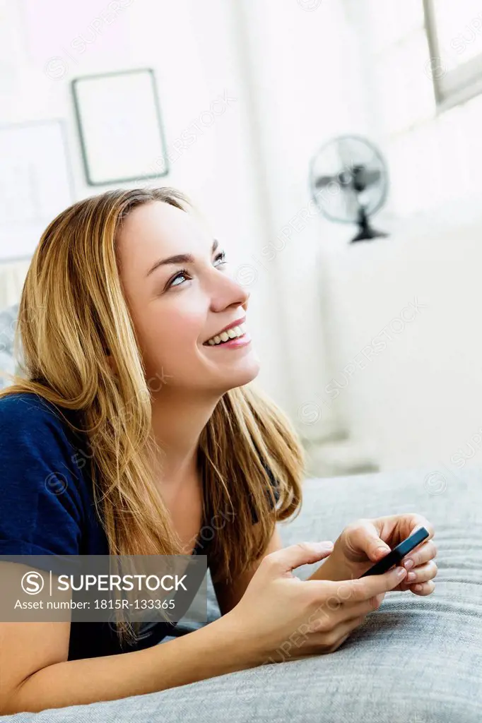 Germany, Bavaria, Munich, Young woman holding mobile phone, smiling