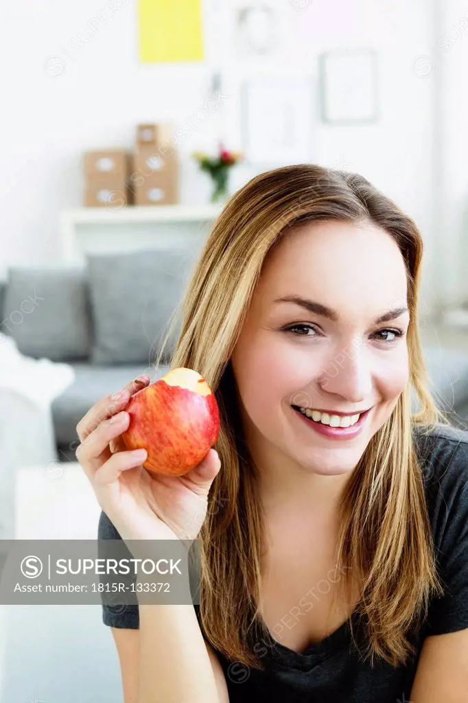 Germany, Bavaria, Munich, Portrait of young woman holding apple, smiling