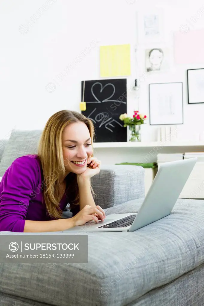 Germany, Bavaria, Munich, Young woman using laptop, smiling