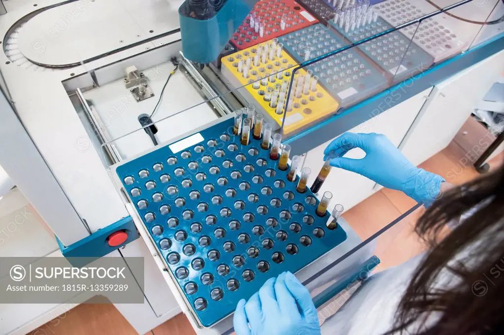 Laboratory technician in analytical laboratory taking test tubes from automated aliquoter