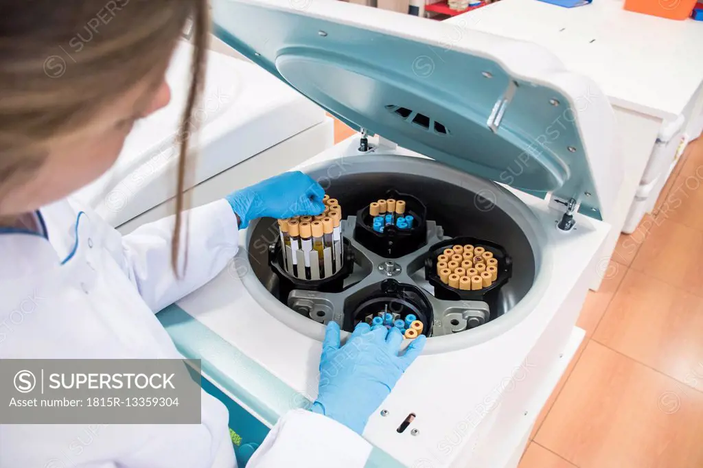 Laboratory technician in analytical laboratory taking test tubes out of centrifuge