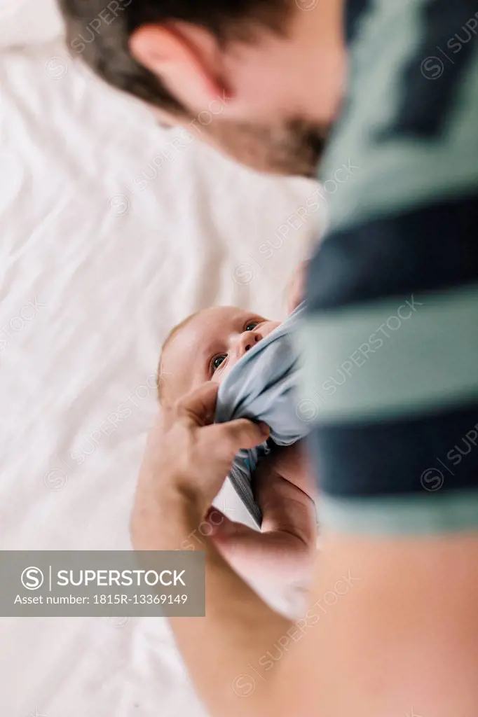 Father with baby boy at home, dressing