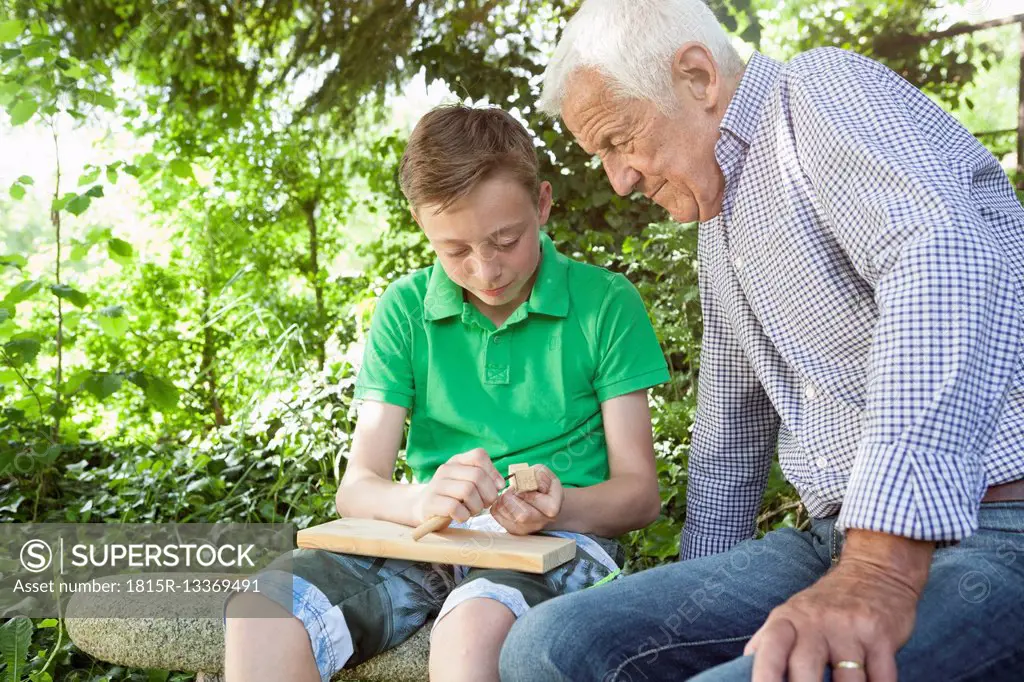 Grandfather and grandson carving together