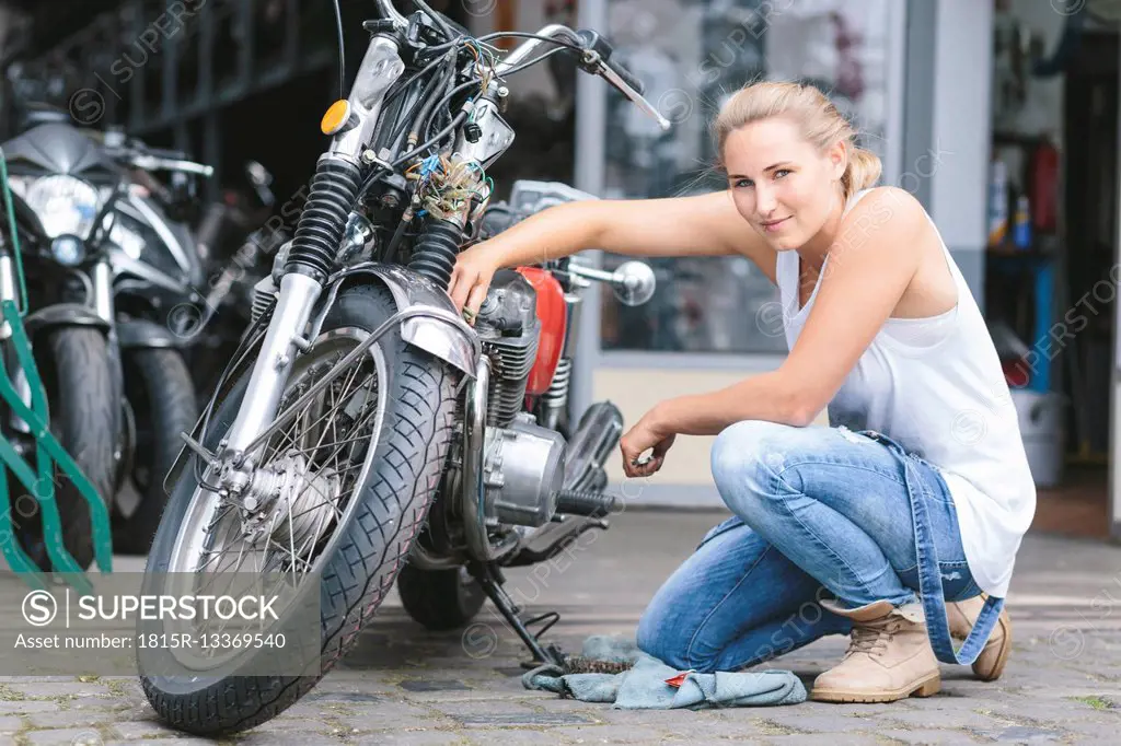 Portrait of smiling young woman next to motorbike