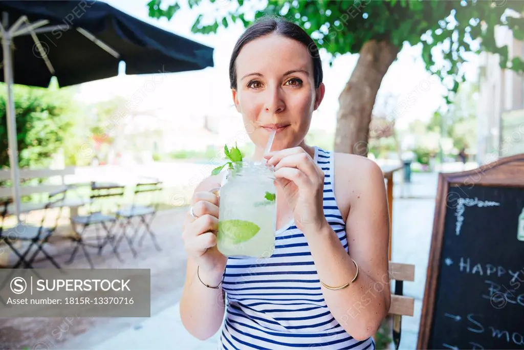 Happy woman drinking homemade lemonade in summer