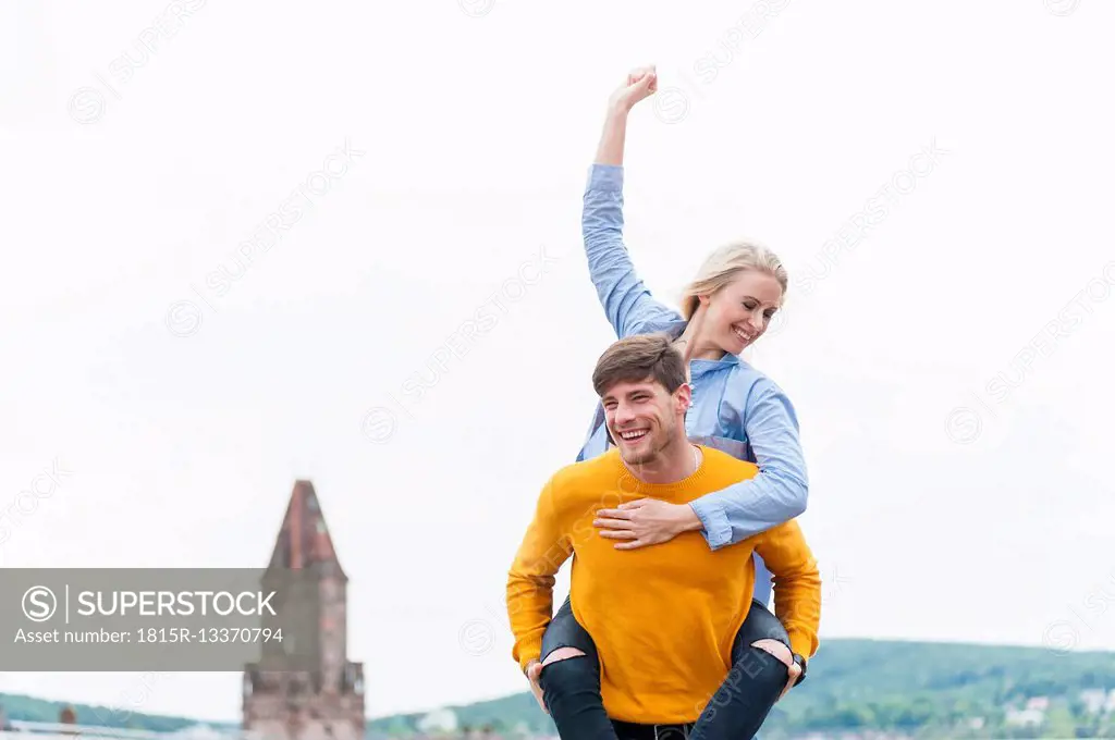 Happy young man carrying his girfriend piggyback