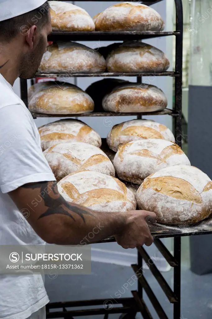 Baker placing a tray of bread in a bakery