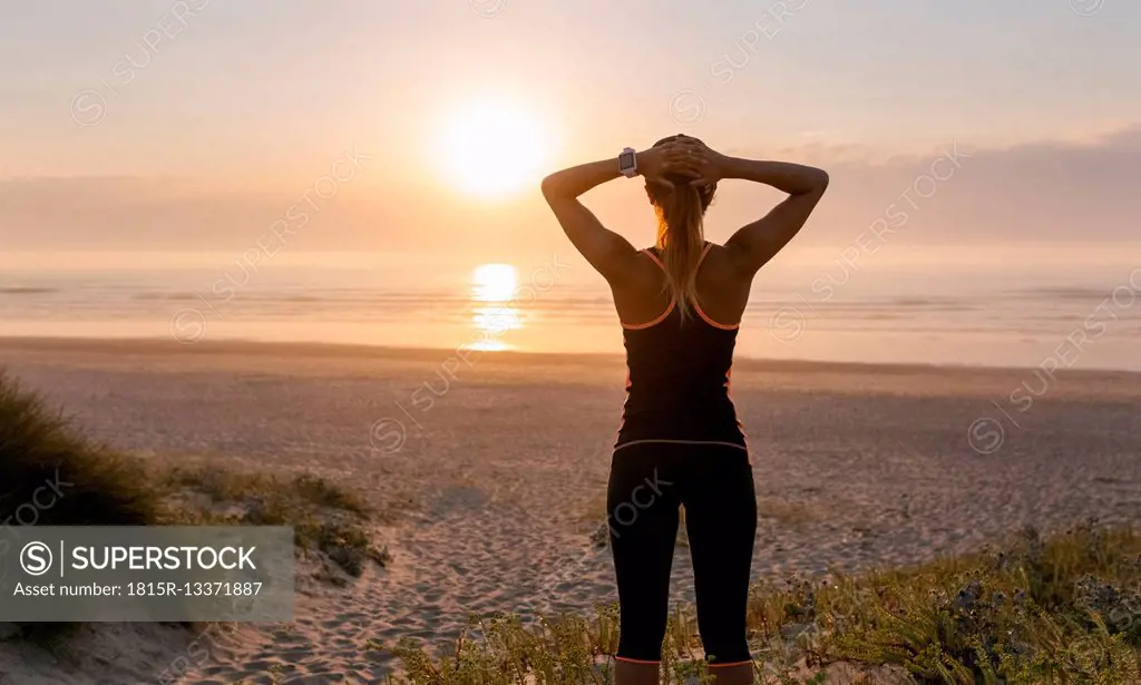 Spain, Aviles, young athlete woman enjoying the sunset on the beach