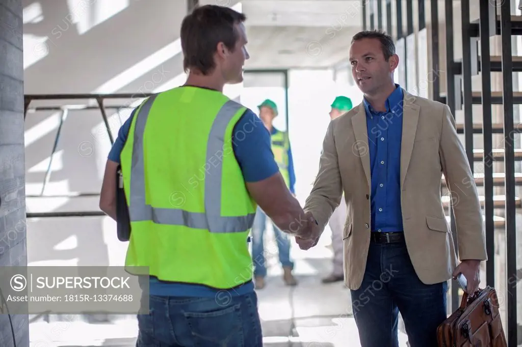 Two men shaking hands on construction site