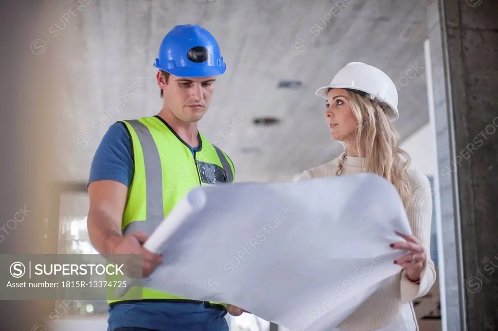 Construction worker and woman looking on construction plan